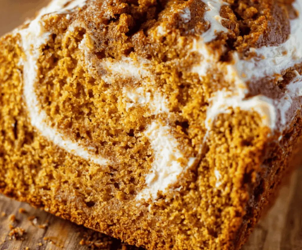 Delicious homemade pumpkin bread with a creamy cream cheese swirl topped with walnuts, perfect for fall baking