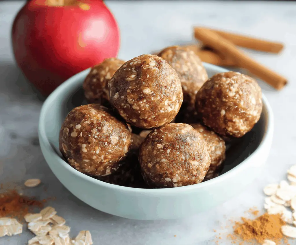 Healthy apple pie energy balls with cinnamon and oats on a wooden surface, perfect for a nutritious snack