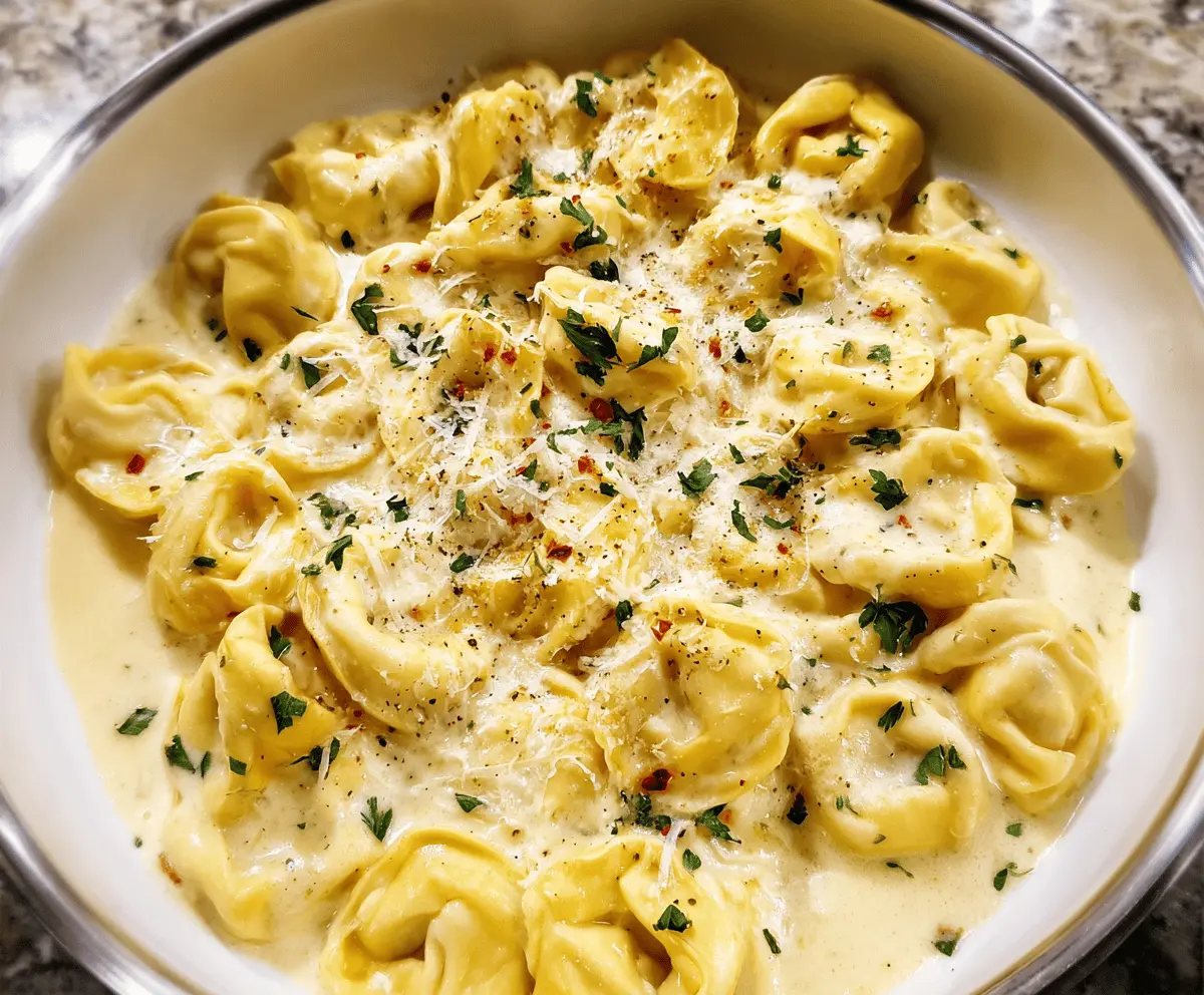 Creamy cheesy Alfredo tortellini pasta served in a bowl, garnished with fresh herbs and grated cheese, perfect for a comforting Italian meal.
