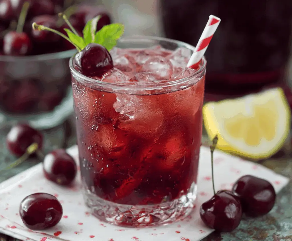 Refreshing Cherry Iced Tea in a clear glass with fresh cherries and mint leaves, perfect for summer hydration.