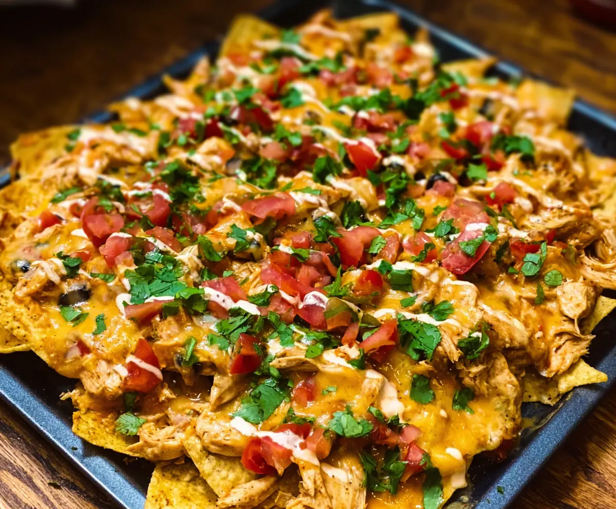 Creamy crockpot chicken nachos topped with melted cheese, fresh salsa, and sour cream.